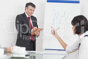Businessman writing on clipboard in office