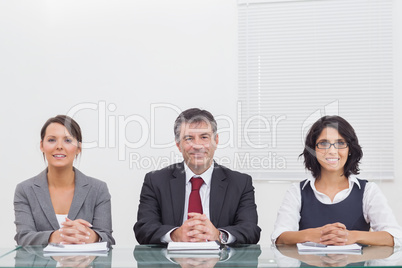 Three business people folding their hands and smiling