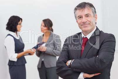 Businessman smiling and two businesswomen speaking