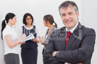 Businessman smiling and three businesswomen speaking