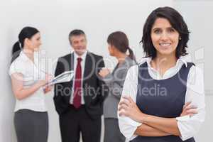 Businesswoman smiling and three business people speaking