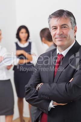 Businessman smiling with arms crossed and three businesswomen sp