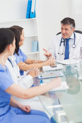 Meeting between a doctor and three nurses smiling