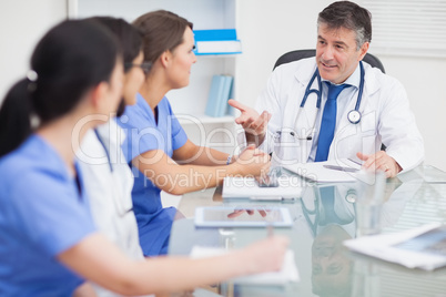 Meeting between a doctor and three nurses and a doctor smiling