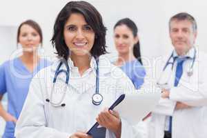 Female doctor with clipboard and her team smiling