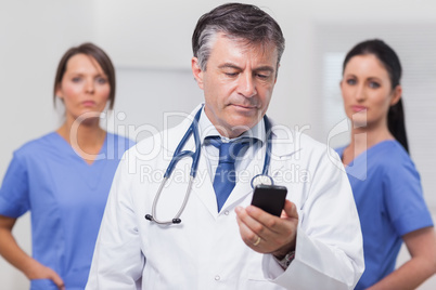 Doctor looking at phone with his team of nurses