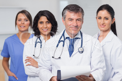 Doctor holding clipboard with his team