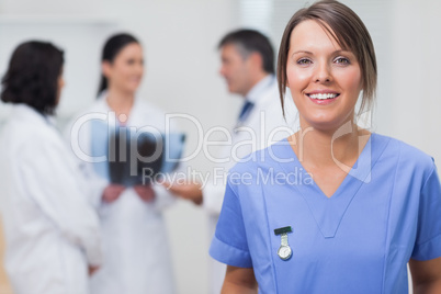 Nurse smiling with her team behind her