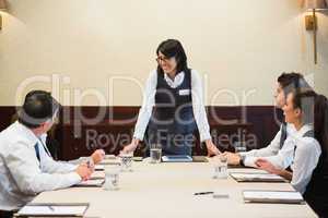 Happy businesswoman standing at head of table
