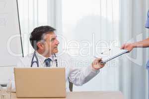 Doctor being handed clipboard