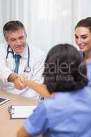 Smiling doctor shaking nurses hand