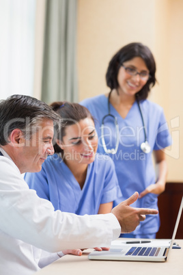 Doctor showing nurses something on laptop