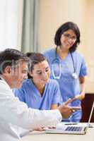 Doctor showing nurses something on laptop