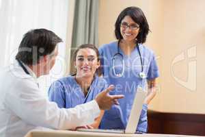 Doctor showing smiling nurses something on laptop