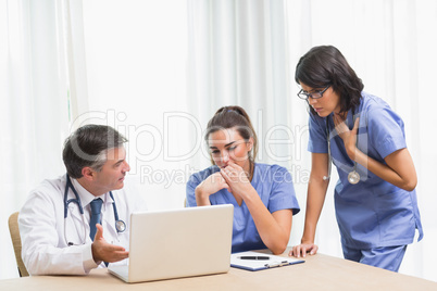 Doctor showing nurses something sad on laptop