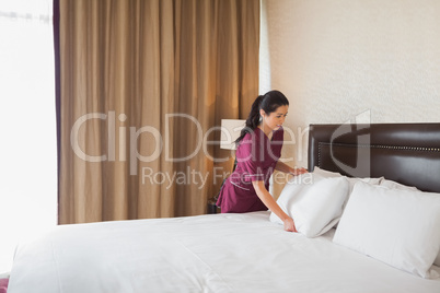 Hotel maid making the bed