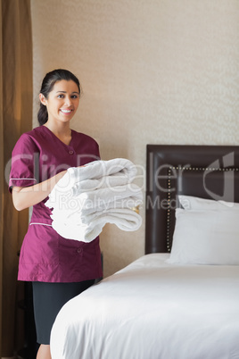 Smiling hotel maid holding towels