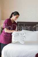 Hotel maid putting towels on bed