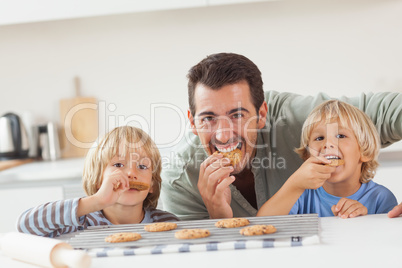Smiling father and his sons eating cookies