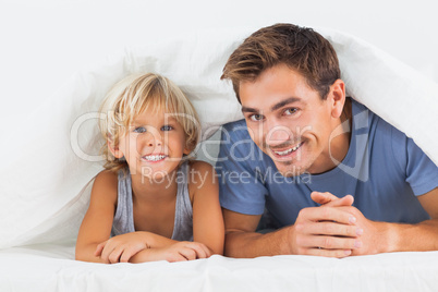 Father and his son lying under the duvet
