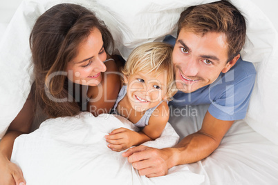 Family lying in the duvet on the bed