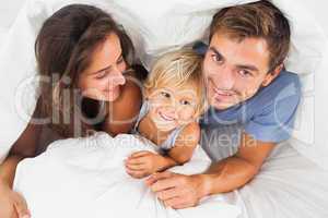 Family lying in the duvet on the bed