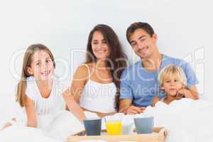Happy family taking the breakfast on the bed