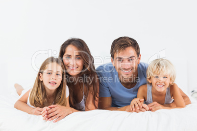 Smiling family lying on a bed