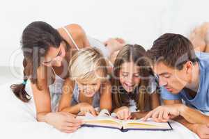 Family reading a book on the bed