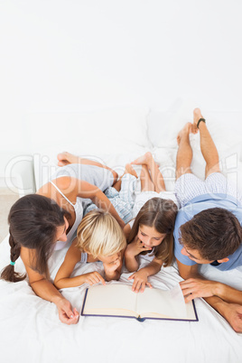 Smiling family reading on the bed