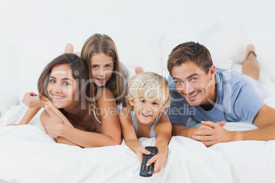 Family lying on the bed with a remote