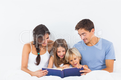 Family sitting with a storybook on the bed