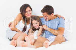 Joyful family sitting on the bed