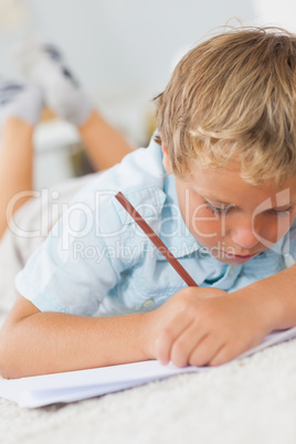Boy writing lying on the floor