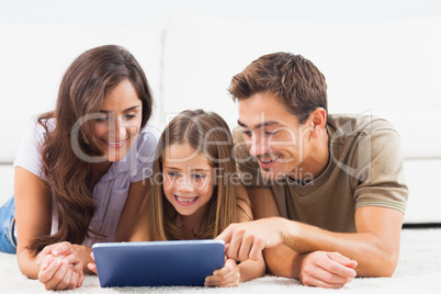 Family lying on a carpet with tablet