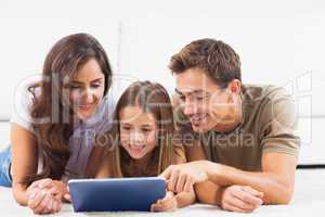 Family lying on a carpet with tablet