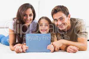 Family with tablet lying on a carpet