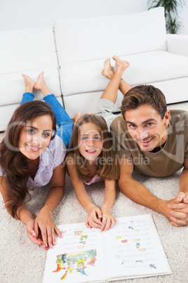 Family with a book lying on a carpet