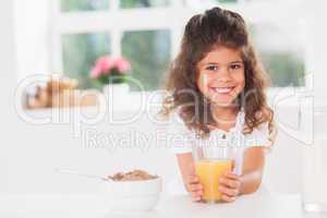 Little girl smiling with her orange juice in hand