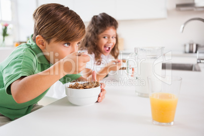 A little boy and a little girl eating cereal