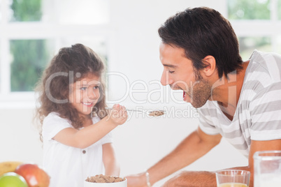 Little girl feeding cereal to father