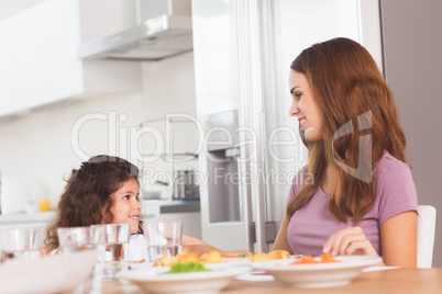 Smiling girl and her mother at the dinner table