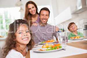 Family smiling at the camera at dinner table