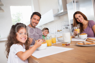 Family smiling at the camera at breakfast
