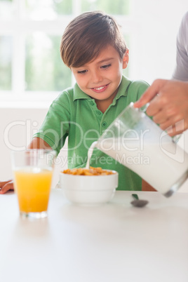 Father pouring milk in the cereal of his son