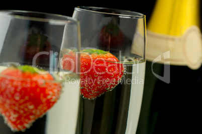 Strawberries floating in two champagne flutes