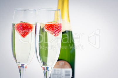 Two champagne flutes with floating strawberries