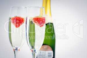 Two champagne flutes with floating strawberries