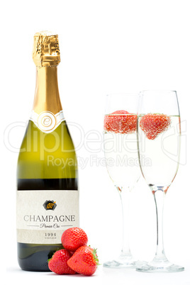 Bottle of champagne with two flutes with floating strawberries