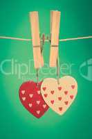 Two heart ornaments hanging from pegs on a line